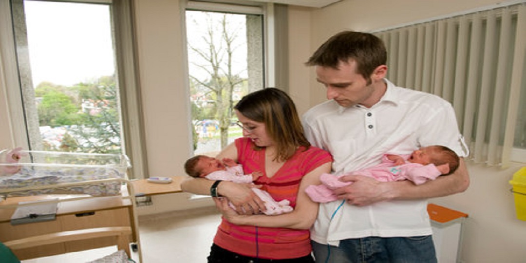 parents holding 2 newborn babies