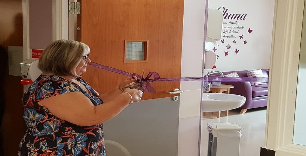 A person cutting a ribbon to an entrance of a room