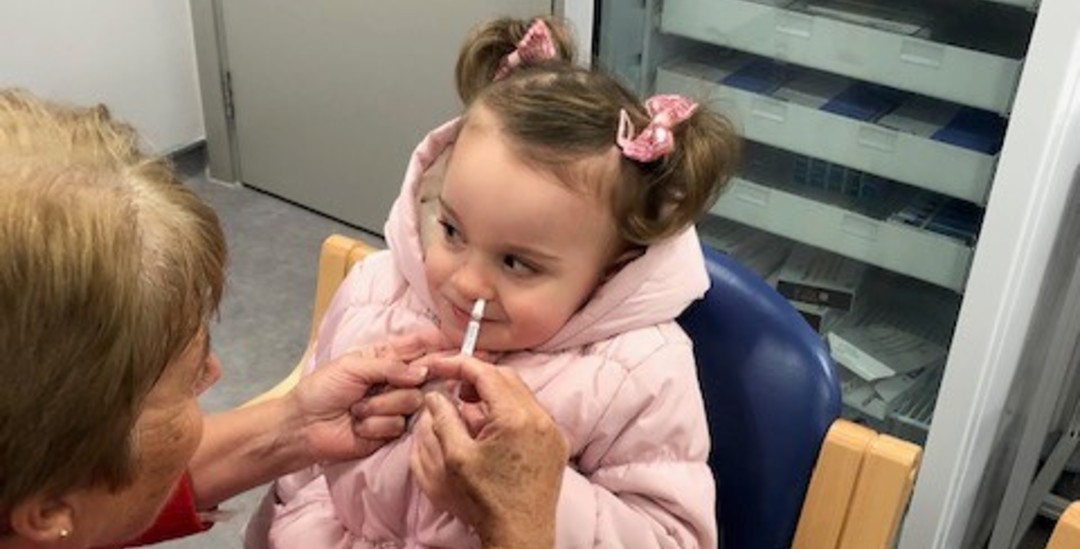 young girl receiving a nasal spray vaccine for the flu