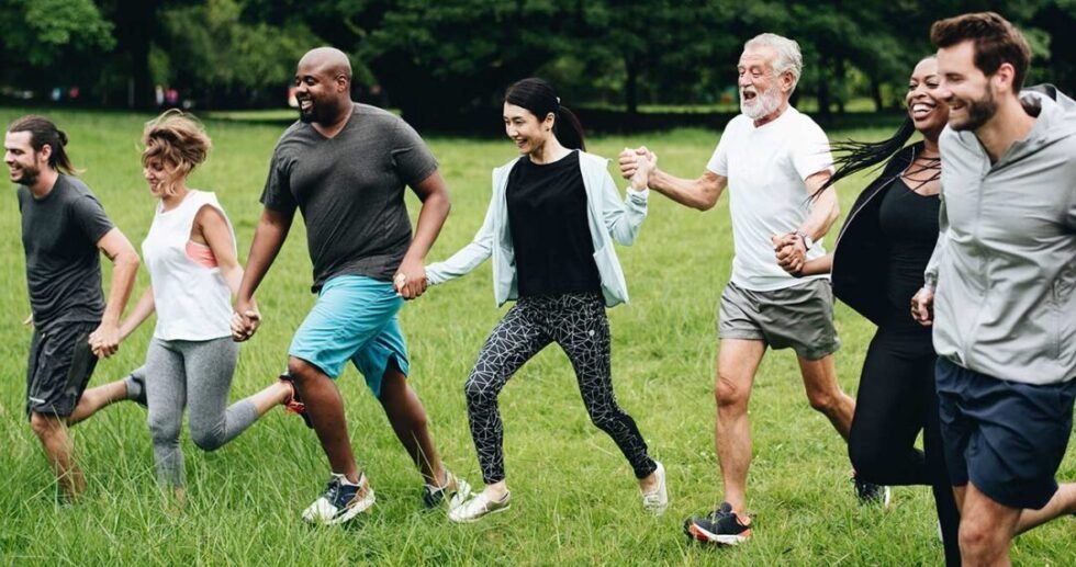 group of people holding hands and running through grass