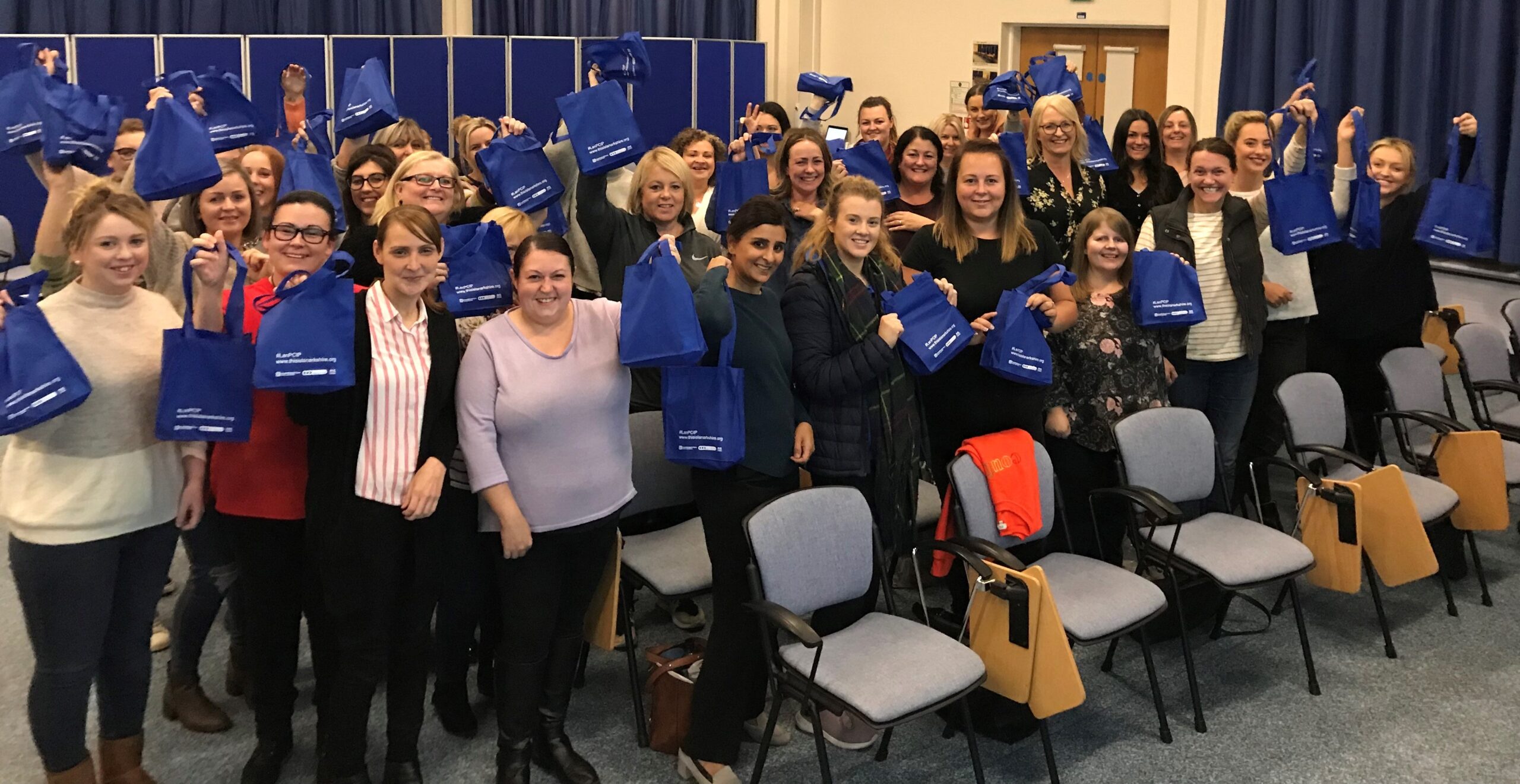 large group of newly recruited community nurses holding blue bags