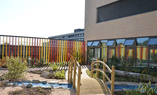 exterior photo of the Lanarkshire Beatson building and a small wooden bridge