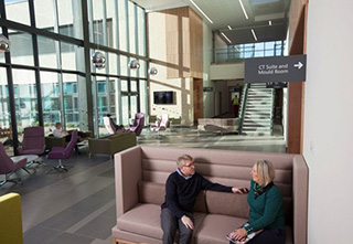 2 people sitting on a large seat inside the Lanarkshire Beatson building