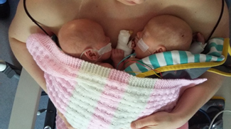 2 newborn babies next to parent