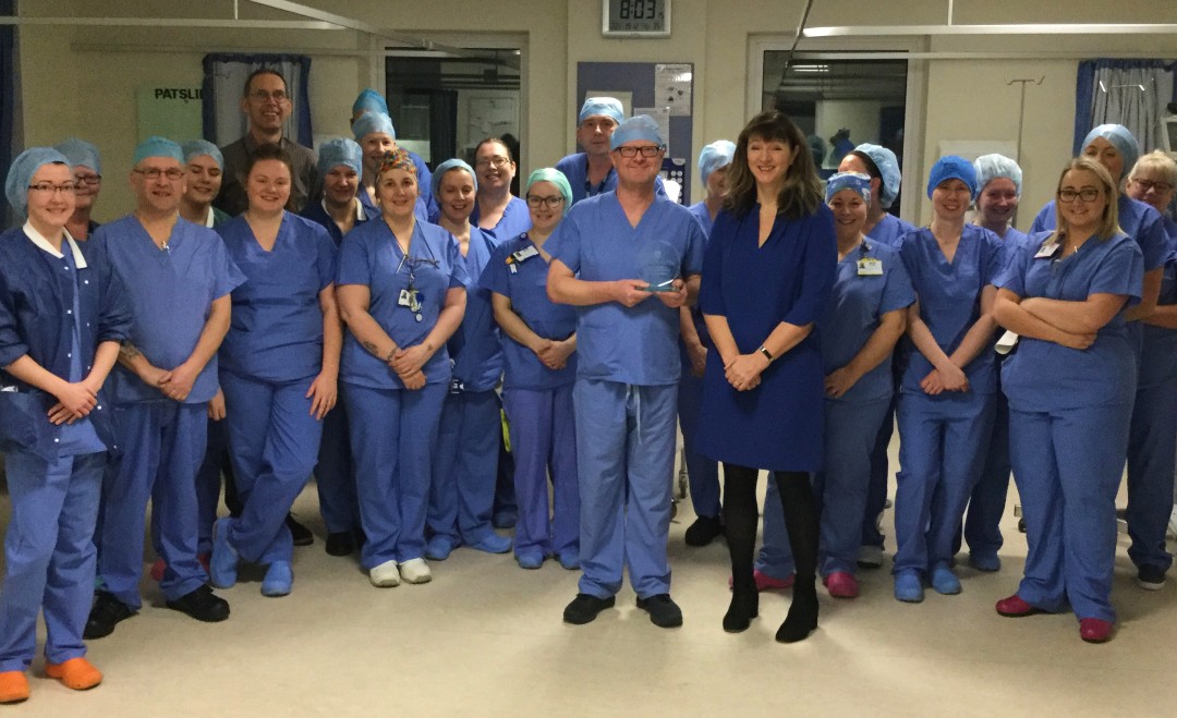 large group of people wearing blue scrubs accepting an award