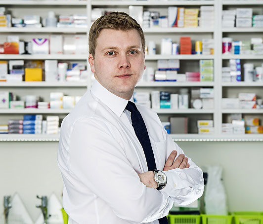Pharmacist standing in a pharmacy surrounded by medicine