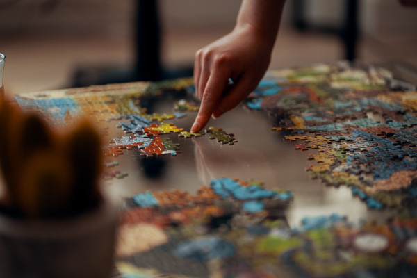 person placing a jigsaw piece in a puzzle