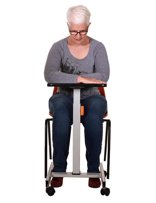 Sit in a chair with a table in front of you.Keep your back straight and lean forward with your forearms on the table. Rest on your forearms and drop your shoulders. Think about your nose tummy breathing.