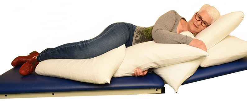 Lie on your side whilst propped-up by pillows. Place your top arm on a pillow in front of you and your top leg on another pillow. Think about dropping your shoulders and using nose tummy breathing.