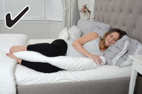 Diagram of a pregnant woman lying correctly on the bed, with a pregnancy pillow between her legs