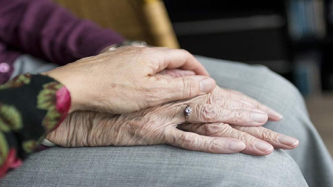 two hands one of top of the other with another hand clasping them