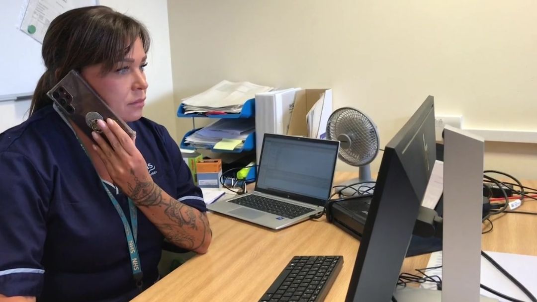 Staff member pictured on the phone talking to a patient and using computer system