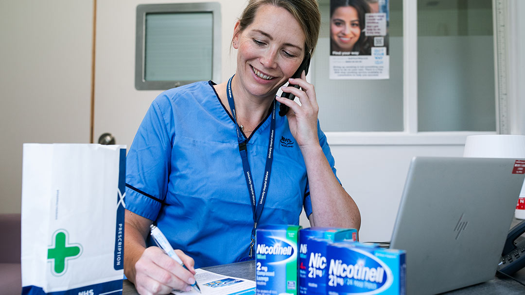 Quit Your Way nurse on the phone at desk with nicotine replacement products showing