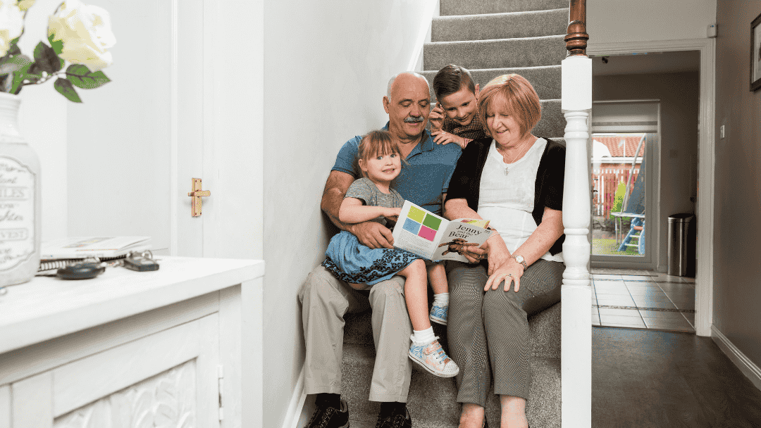 Grandparents sitting on stair with grandchildren reading a book